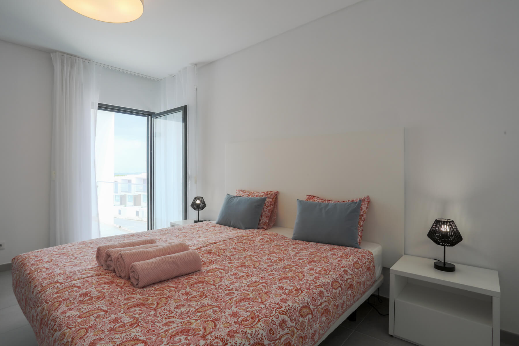 The master bedroom (with cot) is located at the front of the villa, with a balcony overlooking the front garden.