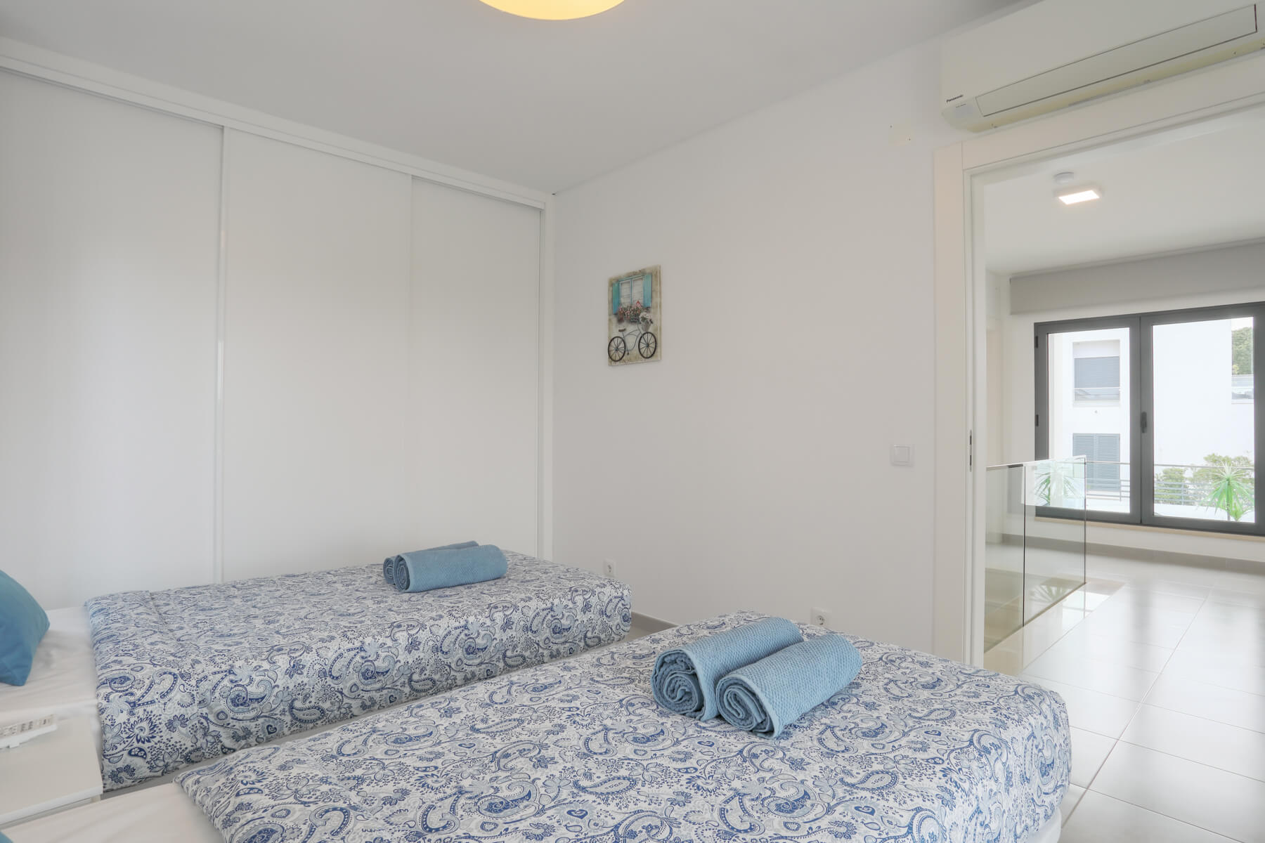 Um quarto espaçoso com acesso direto ao terraço dispõe de um amplo roupeiro com portas de correr e ar condicionado.